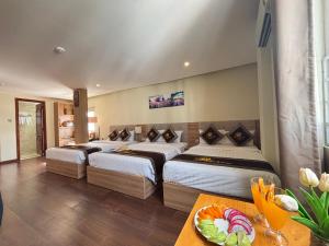 a hotel room with three beds and a table at Sen Vàng Luxury Hotel in Nha Trang
