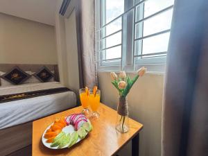 a table with a plate of fruit and a vase of flowers at Sen Vàng Luxury Hotel in Nha Trang +42 photos