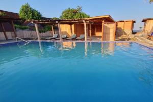 a large swimming pool with chairs and a house at Sunset Moyo Bungalows in Moyo Island