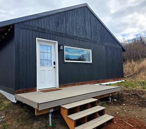 a black building with a door and a porch at Bluff Hideaway - Guest House in Homer