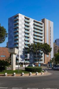 a tall white building with a tree in front of it at Meliá South Beach in Magaluf