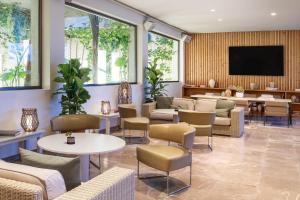 a waiting room with chairs and tables and a flat screen tv at Meliá South Beach in Magaluf