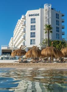 a group of straw umbrellas on a beach with a building at INNSiDE by Meliá Ibiza Beach in San Antonio Bay