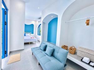 a living room with a blue couch and a bed at TD Santorini Pool Villa in Cổ Lưu (1)