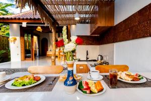 a table with two plates of food on it at Uma Harum Sari by Dhananjaya Hospitality in Penginyahan