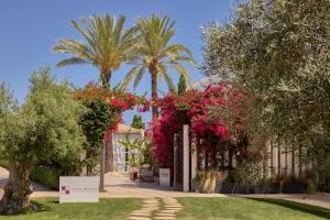 a building with pink flowers and palm trees at ME by Meliá Ibiza - The Leading Hotels of the World in Santa Eularia des Riu