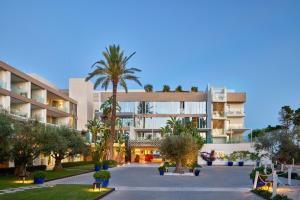 a building with a palm tree in front of it at ME by Meliá Ibiza - The Leading Hotels of the World in Santa Eularia des Riu