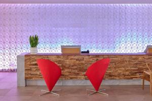 two red chairs in front of a counter at ME by Meliá Ibiza - The Leading Hotels of the World in Santa Eularia des Riu +114 photos