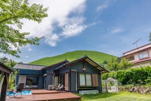 a house with a green hill in the background at ネバーランド伊豆 Neverland IZU in Ito