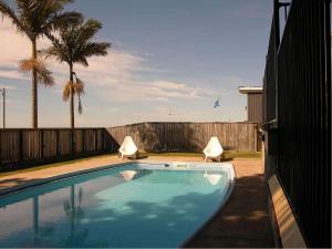 a swimming pool in a backyard with a fence and palm trees at Harbour View Apartments in Ulladulla