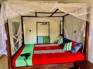 a wooden bed with a red and green comforter at Pelli Riverine in Weligama