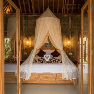 a bedroom with a canopy bed with a heart on it at Sunday Huts Lembongan in Nusa Lembongan +126 photos