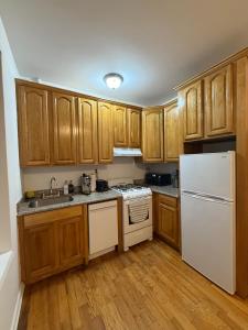 a kitchen with wooden cabinets and a white refrigerator at The atlas - Shared apartment in New York