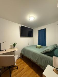 a bedroom with a bed and a desk and a television at The atlas - Shared apartment in New York
