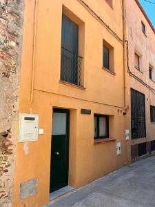 an orange building with a green door and two windows at Can Mariano in Mollet de Perelada