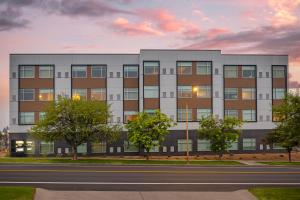 an apartment building with a sunset in the background at Cambria Hotel Bend - Mt Bachelor in Bend