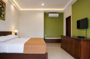a bedroom with a bed and a flat screen tv at mascot hotel senggigi in Senggigi