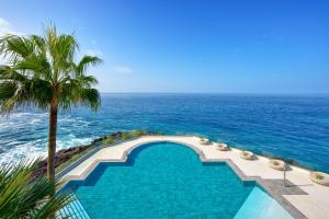 a swimming pool with a palm tree and the ocean at Meliá La Palma in Puerto Naos