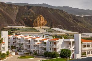 a row of white apartment buildings in front of a mountain at Apartments La Palma, Affiliated by Meliá in Puerto Naos