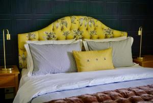 a bed with a yellow headboard and some pillows at Willowtree Cottage Gated Country Luxury Near Lincoln Uni & Wedding Venues in Lincoln