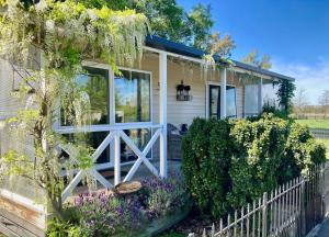 a cottage with a white fence and purple flowers at Willowtree Cottage Gated Country Luxury Near Lincoln Uni & Wedding Venues in Lincoln