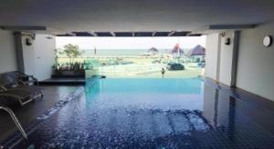 a large swimming pool with a view of the ocean at The High One in Ban Laem Thaen
