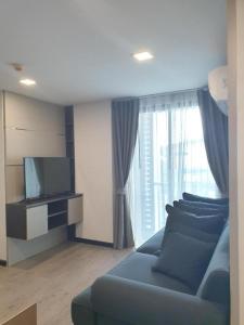 a living room with a blue couch and a tv at The High One in Ban Laem Thaen