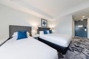 two beds in a hotel room with blue pillows at Hotel Kingsley in Brisbane