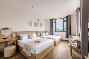 a hotel room with two beds and a mirror at DO Hotel in Da Lat
