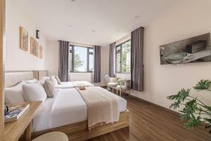 a white bedroom with a bed and a table at DO Hotel in Da Lat
