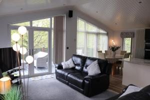 a living room with a black leather couch and a table at High View Lodge in Windermere