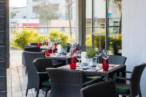 a row of tables and chairs with wine glasses on them at Hotel Wolfsburg Centrum, Affiliated by Meliá in Wolfsburg