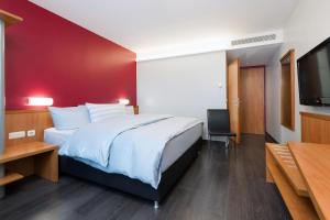 a bedroom with a large bed with a red wall at Hotel Wolfsburg Centrum, Affiliated by Meliá in Wolfsburg +31 photos