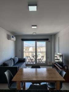 a living room with a table and a large window at Caleta VIEW - Alojamientos in Puerto Madryn