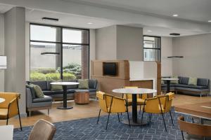 a lobby with tables and chairs and a tv at Courtyard by Marriott Bloomington in Bloomington