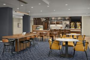 a restaurant with tables and chairs and a bar at Courtyard by Marriott Bloomington in Bloomington