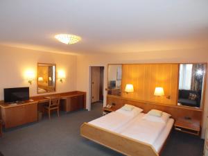 a bedroom with a bed and a desk and a television at Hotel Stadt Pasing in Munich