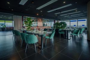 a dining room with tables and green chairs at INNSiDE by Meliá Düsseldorf Hafen in Düsseldorf
