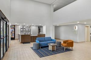 a waiting room with a blue couch and two chairs at Garner Hotel Warren Northwest by IHG in Warren