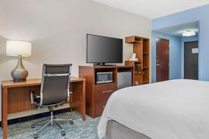 a hotel room with a bed and a desk with a television at Garner Hotel Warren Northwest by IHG in Warren