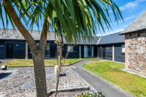 a palm tree in front of a building at Braddon - Treworgie Barton Cottages in Bude