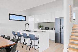 a kitchen with a white counter and bar stools at The Bay View San Remo by Ready Set Stay- BYO LINEN & TOWELS in San Remo