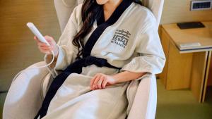a woman in a kimono holding a remote control at Mitasuya Ryokan Hotel Daejeon Yuseong in Daejeon
