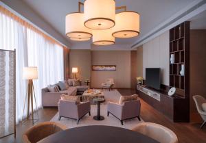 a living room with a couch and chairs and a television at Zhenjiang Marriott Hotel in Zhenjiang