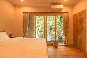a bedroom with a bed and a large window at Neduh House Pererenan in Pererenan +18 photos