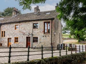 an old stone house with a fence around it at Bay Horse Cottage in Skipton