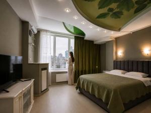 a woman standing in a bedroom looking out the window at Апартаменти Мост Сіті in Dnipro