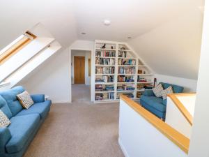 a living room with blue couches and a book shelf at Whitehouse Woodwrae in Forfar