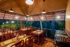 a restaurant with tables and chairs and a large window at Wood Panda Luxury Resort Wayanad in Meppādi