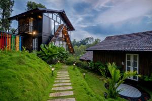 a house on a grassy hill next to a house at Wood Panda Luxury Resort Wayanad in Meppādi